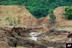 People gather in front of the broken banks of the Patel dam near Solai, in Kenya's Rift Valley, May 10, 2018.