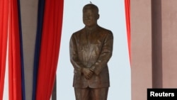 A bird stands on the head of a statue of the late King Norodom Sihanouk during the statue's unveiling ceremony in central Phnom Penh, Oct. 11, 2013.
