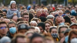 A child sits on a man's shoulders as Hungarian opposition supporters listen to a speech by Prime Minister candidate Peter Marki-Zay during celebration the 65th anniversary of the 1956 Hungarian revolution, in Budapest, Oct. 23, 2021.