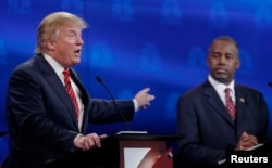 U.S. presidential candidate and businessman Donald Trump, left, speaks as Ben Carson, a retired neurosurgeon, listens at the 2016 U.S. Republican presidential candidates debate held by CNBC in Boulder, Colo., Oct. 28, 2015.