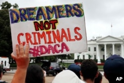 FILE - A woman holds up a signs in support of Deferred Action for Childhood Arrivals, or DACA, during an immigration reform rally at the White House in Washington, Aug. 15, 2017.