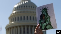 FILE - An activist holds up a pro-refugee image during a demonstration outside the U.S. Capitol in Washington, Oct. 15, 2019.