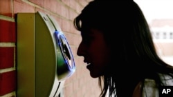 FILE - A woman uses an iris scanner to enter an elementary school in Freehold, N.J. Those who choose to register with the system can use the iris-scanning camera to unlock doors automatically. The African region of Somaliland has become the first to use such a biometric system to identify voters and prevent duplicate voting.