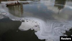 Workers sail on a boat as they clean up a polluted river in Jiaxing, Zhejiang province, China, July 13, 2013. 