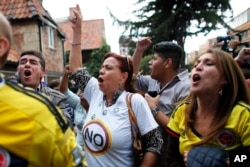 Opponents to the peace deal signed between the Colombian government and rebels of the Revolutionary Armed Forces of Colombia, FARC, celebrate as they listen to the results of the referendum to decide whether or not to support a peace accord to in Bogota, Colombia, Sunday, Oct. 2, 2016.