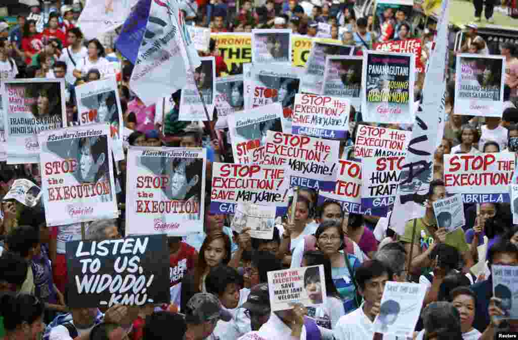 Activists display placards as they march towards Indonesian embassy, to hold a candlelight vigil for death row prisoner Mary Jane Veloso in Makati, Philippines, April 28, 2015.