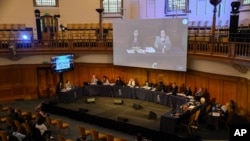 Witness Qelbinur Sidik, left on stage and left on screen above, give an evidential statement to the Panel of the independent Uyghur Tribunal during the first session of the hearings in London, June 4, 2021.