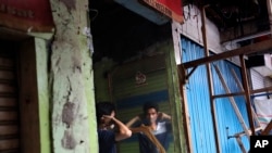 A man uses a mirror to put on a face mask at a market closed due to the coronavirus outbreak in Jakarta, Indonesia, April 10, 2020.