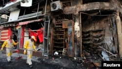 Municipal workers clean the site of a bomb attack in Baghdad's Karrada district, Feb. 18, 2014. 
