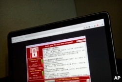 FILE - Screenshot of the warning screen from a purported ransomware attack, as captured by a computer user in Taiwan, is seen on a laptop in Beijing, May 13, 2017.