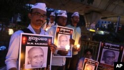 FILE - Supporters of India’s Aam Aadmi Party (AAP), or Common Man's Party, hold portraits of scholar Malleshappa M. Kalburgi during a candlelight vigil Tuesday in Bangalore to protest his weekend killing.