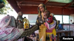 FILE - A handout photograph, shot in January 2024, shows a woman and baby at the Zamzam displacement camp, close to El Fasher in North Darfur, Sudan.