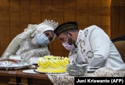 Pengantin perempuan Irra Chorina Octora dan pasangan Turki-nya Yavuz Ozdemir, mengenakan masker wajah di tengah kekhawatiran virus corona COVID-19, berbicara selama upacara pernikahan mereka di Surabaya pada 25 Maret 2020, sebagai ilustrasi. (Foto: AFP/Juni Kriswanto)