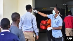A worker checks the temperature of travelers at the border post with Kenya in Namanga, northern Tanzania, on March 16, 2020.