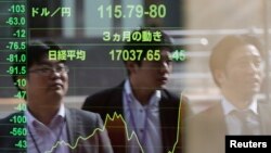 Pejalan kaki memperhatikan papan elektronik yang menampilkan angka indeks Nikkei dan nilai tukar Yen di depan perusahaan sekuritas di Tokyo. (Foto:dok)