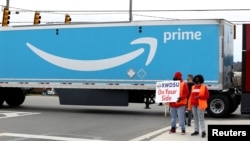 People hold a banner at the Amazon facility as members of a congressional delegation arrive to show their support for workers who will vote on whether to unionize, in Bessemer, Alabama, March 5, 2021. 