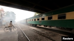 FILE - A man waits to cross a portion of track once shared with the Karachi Circular Railway line in Karachi, Pakistan, May 24, 2017.