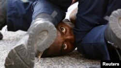 A man protesting the shooting death of Alton Sterling is detained by law enforcement near the headquarters of the Baton Rouge Police Department in Baton Rouge, Louisiana, July 9, 2016. 