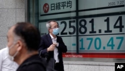Men walk past an electronic stock board showing Japan's Nikkei 225 index at a securities firm in Tokyo, July 27, 2020.