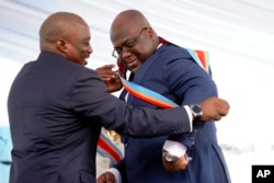 Congolese President Felix Tshisekedi, right, receives the presidential sash from outgoing president Joseph Kabila after being sworn in in Kinshasa, Democratic Republic of the Congo, Thursday Jan. 24, 2019.