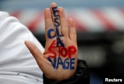 A woman displays her hand with the message "Stop slavery" as she attends a protest against slavery in Libya outside the Libyan Embassy in Paris, France, Nov. 24, 2017.