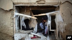 FILE - A boy inspects his damaged home after an attack near the Bagram Air Base, Afghanistan, Dec. 11, 2019. A United Nations report says more than 100,000 Afghan civilians have been killed or hurt in the last 10 years.