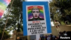 FILE - A member of the LGBT community holds a placard with the picture of Russia's President Vladimir Putin during a protest outside the Russian Embassy against discrimination and violence aimed at gays in Chechnya and other regions of Russia, in Mexico City, Mexico, April 19, 2017.