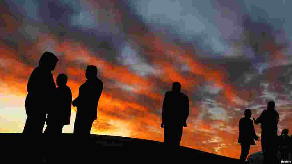 Kurdish civilians stand atop a hill overlooking Kobani, near the Mursitpinar border crossing on the Turkish-Syrian border in the southeastern town of Suruc in Sanliurfa province, Nov. 3, 2014. 