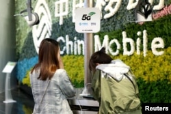FILE - Customers are seen at a China Mobile flagship store displaying smart home experience with 5G network, in Shanghai, China, March 10, 2019.