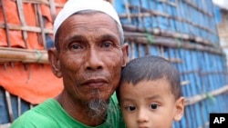 A Rohingya refugee sits with a child at the Kutupalong Rohingya refugee camp in Cox's Bazar, Bangladesh, June 2, 2020. 