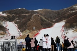 FILE - Journalists stand in front of ski slopes during an organized media tour to the National Alpine Skiing Center, a venue of the 2022 Winter Olympic Games, in Beijing's Yanqing district, China, Feb. 5, 2021.