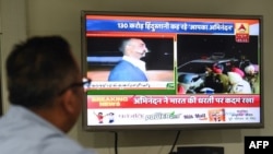 An Indian man watches live news channels broadcasting images of Indian Air Force (IAF) Wing Commander pilot Abhinandan Varthaman returning to India from the India-Pakistan Wagah border on March 1, 2019. (Photo by Prakash SINGH / AFP)