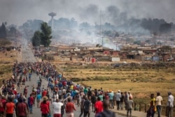 A mob armed with spears, batons and axes run through Johannesburg's Katlehong Township during anti-foreigner violence, Sept. 5, 2019.