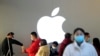 Orang-orang mengenakan masker antre untuk diperiksa suhu di sebuah Apple Store di Shanghai, China, 21 Februari 2020. (Foto: Reuters)