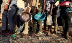 Ethiopian refugees who fled the country's restive Tigray region queue to receive food aid at the Um-Rakoba camp in Al-Qadarif state, in Sudan, Dec. 11, 2020.