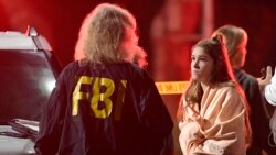 Un agent du FBI s'entretient avec un témoin près de la scène de la tuerie du 8 novembre 2018, à Thousand Oaks, en Californie, où un homme armé a ouvert le feu à l'intérieur d’un bar lors d’une soirée universitaire, tuant 12 personnes et en blessant plusieurs autres.