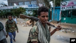 FILE - Fighters loyal to the Tigray People's Liberation Front walk along a street in the town of Hawzen, then controlled by the group, in the Tigray region of northern Ethiopia, May 7, 2021. 