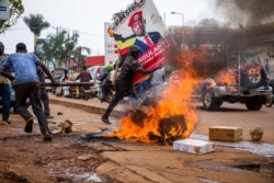 A supporter of Ugandan musician-turned-politician Robert Kyagulanyi, also known as Bobi Wine, carries his poster during a protest against the arrest of Kyagulanyi, during his campaign rally in Kampala, Uganda, Nov. 18, 2020.