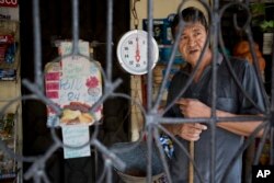 In this Oct. 31, 2018 photo, store owner Carlos Alfonso Garcia looks out from behind his iron gate in the Ciudad Planeta neighborhood of San Pedro Sula, Honduras. The bars that hem in nearly every porch in one of the most dangerous neighborhoods.
