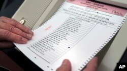 FILE - Nick Zaharias loads a test ballot into a vote-counting machine while testing machines before the New Hampshire primary in Derry, New Hampshire, Jan. 16, 2024.