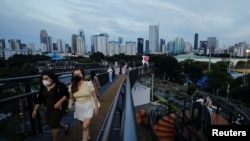 People wearing protective face masks enjoy a stroll along a skywalk bridge as the Omicron coronavirus variant continues to spread, in Jakarta, Indonesia, Feb.y 7, 2022. 