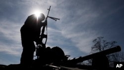 FILE - A Ukrainian soldier stands atop a military vehicle near Artemivsk, eastern Ukraine, Feb. 23, 2015.