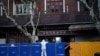 FILE - A person in a protective suit looks over barricades set around a sealed-off area, during a lockdown to curb the spread of the coronavirus disease (COVID-19) in Shanghai, China, April 11, 2022.