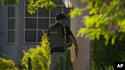 FILE - A police officer unholsters his gun while investigating the stabbing death of Las Vegas Review-Journal investigative reporter Jeff German, in Las Vegas, Sept. 7, 2022.