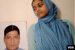 A 17-year-old girl is seen at her Dhaka home with a photo of her father, Ismail Hossain Baten. Since Baten was picked up by members of a security agency in 2019, his family has been running from pillar to post in search of him. (Enam Islam for VOA)