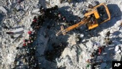Rescuers and residents search through the rubble of collapsed buildings in the town of Harem near the Turkish border, Idlib province, Syria, Feb. 8, 2023. 