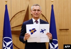 Sekretaris Jenderal NATOJens Stoltenberg menunjukkan dokumen permohonan keanggotaan NATO yang diajukan oleh Swedia dan Finlandia, di Brussels,18 Mei 2022. (Foto: Johanna Geron/Pool via AFP)