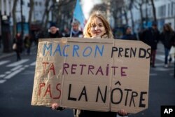 A protestor holds a placard reading 'Macron take your pension instead of ours' during a rally against the French President's pension reform, in Paris, Jan. 21, 2023.