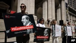 FILE - Participants hold signs during a reading event in solidarity of support for author Salman Rushdie outside the New York Public Library, Aug. 19, 2022, in New York.