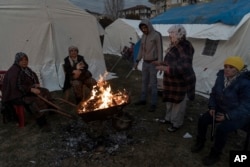 People keep warm next to a fire at a camp for survivors of the earthquake in Gaziantep, Turkey, Feb. 10, 2023.